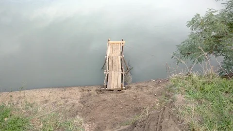 The bridge of pine boards on the bank of the river for fishing with a rod Stock Footage 97695883