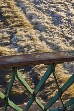 Bridge railing over fast-flowing foamy river Foto stock