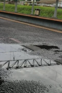 Bridge Reflection in Road Puddle Stock Photos