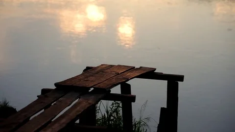 The bridge in the river at dusk. The water reflects the setting sun Stock Footage 79793451