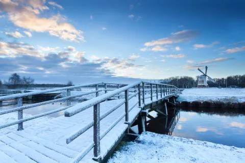 Bridge via river to windmill in winter Stock Photos