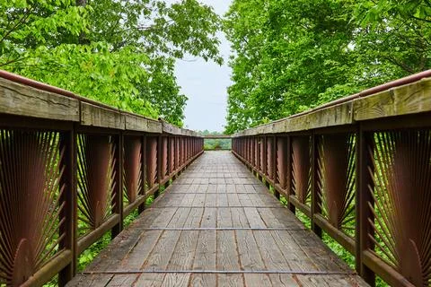 Bridge with rusty rising sun pattern on railing with worn wooden plank path Stock-Fotos