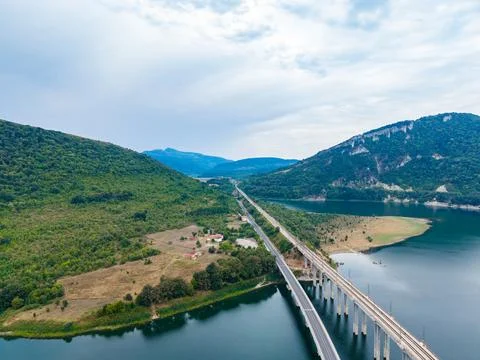 A bridge spans across a river surrounded by green hills. The area has open la Stock-Fotos