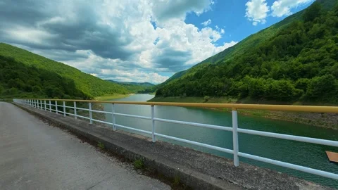 Bridge spans calm lake, framed by lush green hills. Zavoj Lake, Serbia Stock Footage 337490257