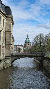 A bridge spans over the river with a building in the background Hanover Germany Stock Photos