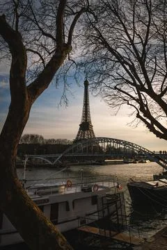A bridge spans a river with a large Eiffel tower in the background Stock Photos