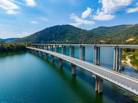 Bridge spans a river with mountains in the background under a clear sky dur.. Stock Photos