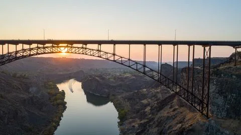 A bridge spans a river with a sunset in the background Stock Photos