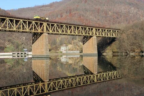 A bridge spans a river with a train crossing it Stock Photos