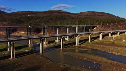 Bridge spans river under blue sky near forest in rural area Stock Footage 336547308