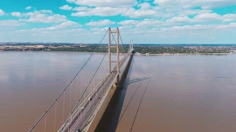 Bridge spans wide river under bright blue sky Vidéo 343545698