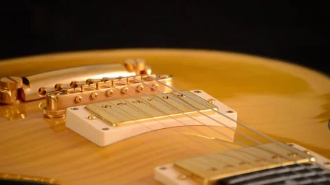 Bridge, strings and pickup of electric guitar gyrating on black background Video stock 78556530