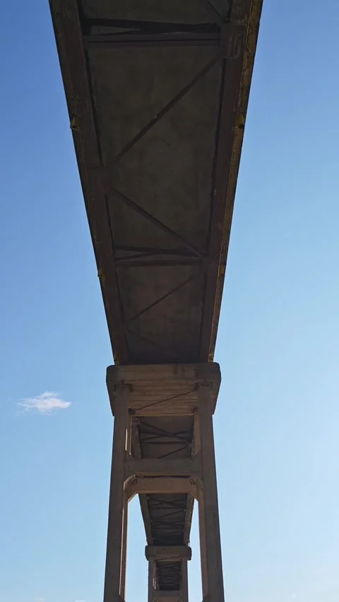 Bridge structure seen from below against blue sky Vidéo 312122366