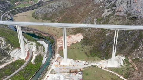 Bridge (viaduct) supported by pillars spanning gorge with river and valley Stock Footage 152851865