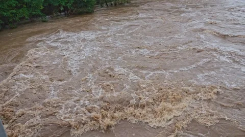 Bridge view of a river that has burst its banks, flooding nearby fields and.. Video stock 285596967