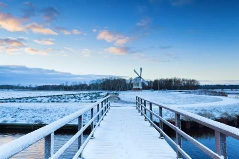 Bridge to windmill in snowy winter Stock Photos