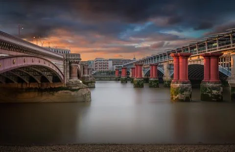 Bridges spanning a river at sunset with reflections and moody skies Stock Photos