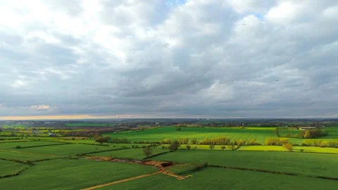 Bright agricultural fields forming geometric patterns across rolling countryside Stock Footage 334325865