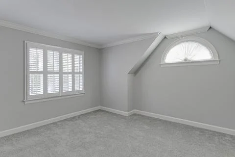 Bright And Clean Empty Room With White Shutters And Carpeted Flooring. Stock Photos