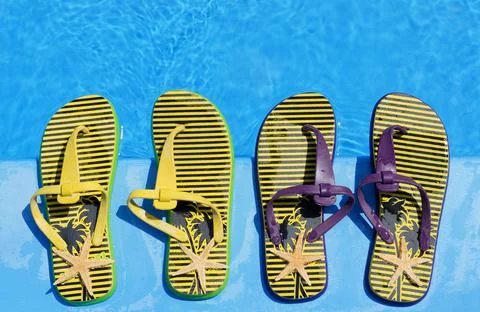 Bright and colorful flip-flops with starfish on the background of the pool. Stock Photos