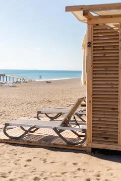 Bright and inviting beach scene featuring wooden lounge chairs positioned on  Stock Photos