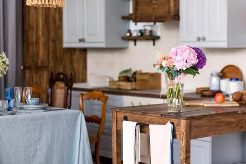 Bright and inviting kitchen interior featuring a wooden table with a vase of Stock Photos