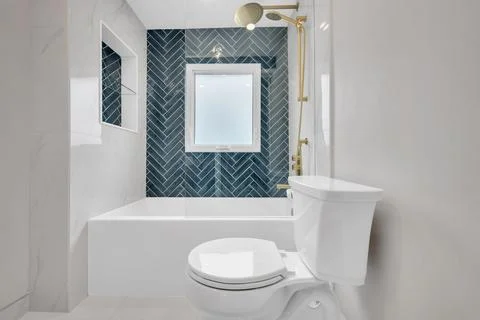 Bright and modern bathroom featuring herringbone tile accents and gold fixt.. Фото