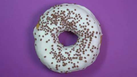 Bright and white glazed donut with chocolate balls, macro shot, spinning on a Stock Footage 89729258