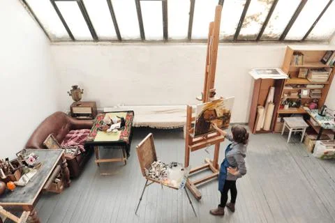 Bright art studio with a large window. Easels and canvases. Woman artist paints Stock Photos