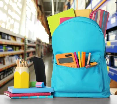 Bright backpack with school stationery on table in shopping mall 库存照片