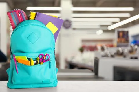Bright backpack with school stationery on table in shopping mall. Space for t Stock Photos