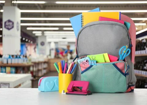 Bright backpack with school stationery on table in shopping mall Stock Photos