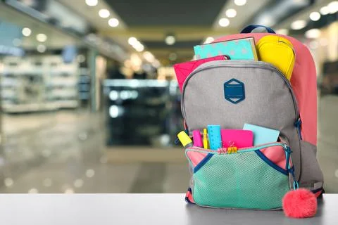 Bright backpack with school stationery on table in shopping mall. Space for t Stock Photos