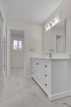 Bright bathroom featuring a marble vanity top and modern lighting fixture. Fotos de archivo