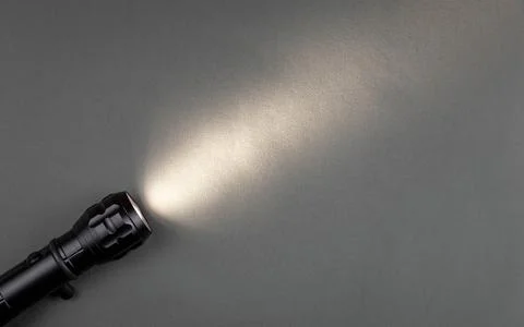 A bright beam of light from a flashlight shines on a gray background Stock Photos