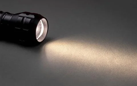 A bright beam of light from a flashlight shines on a gray background Stock Photos
