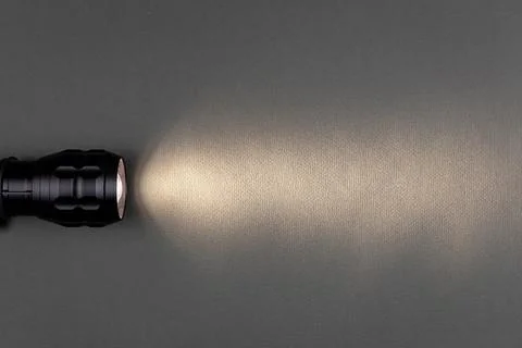 A bright beam of light from a flashlight shines on a gray background Stock Photos