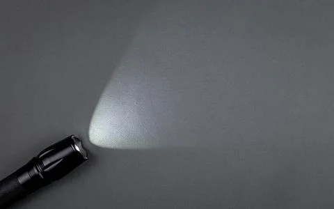 A bright beam of light from a flashlight shines on a gray background Stock Photos