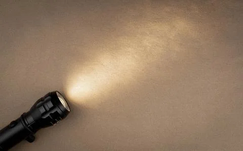 A bright beam of light from a flashlight shines on a brown recycled craft pap Stock Photos