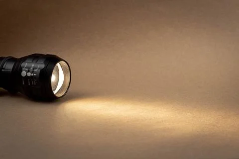 A bright beam of light from a flashlight shines on a brown recycled craft pap Stock Photos