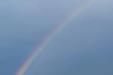 Bright beautiful multi-colored rainbow after a summer rain on a blue cloudles 스톡 사진