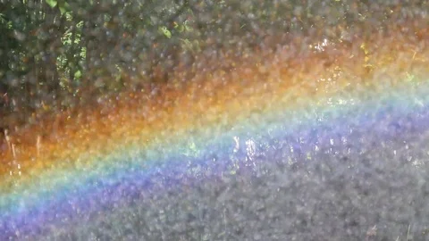 Bright beautiful rainbow close-up during the rain. Artificial rain makes Stock Footage 119969225