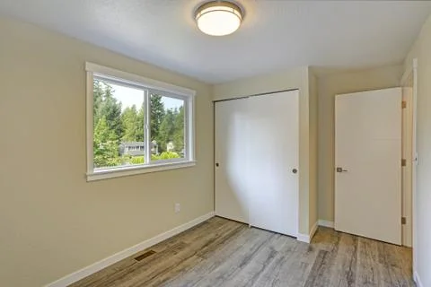 Bright beige empty room with grey hardwood floor, built-in closet. American h Stock Photos