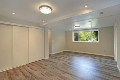 Bright beige large empty room with hardwood floor, built-in closet, small win Foto stock