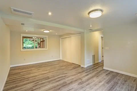 Bright beige large empty room with hardwood floor, built-in closet, small win Stock Photos
