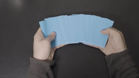Bright Blue Cards Displayed in Hands then Straightened Stock Footage 100555079