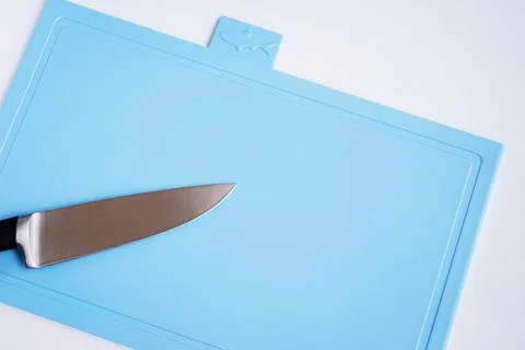 Bright blue clean plastic cutting board with a kitchen knife on a white Stock Photos