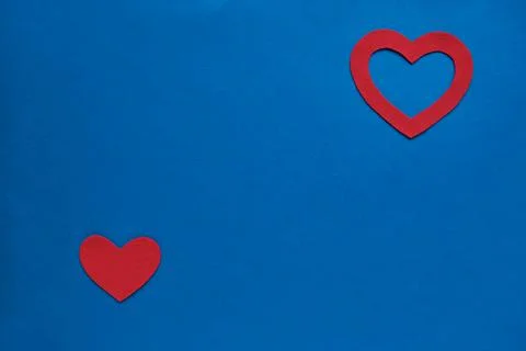 Bright blue flat background with two red hearts cut out of each other, perpen Stock Photos