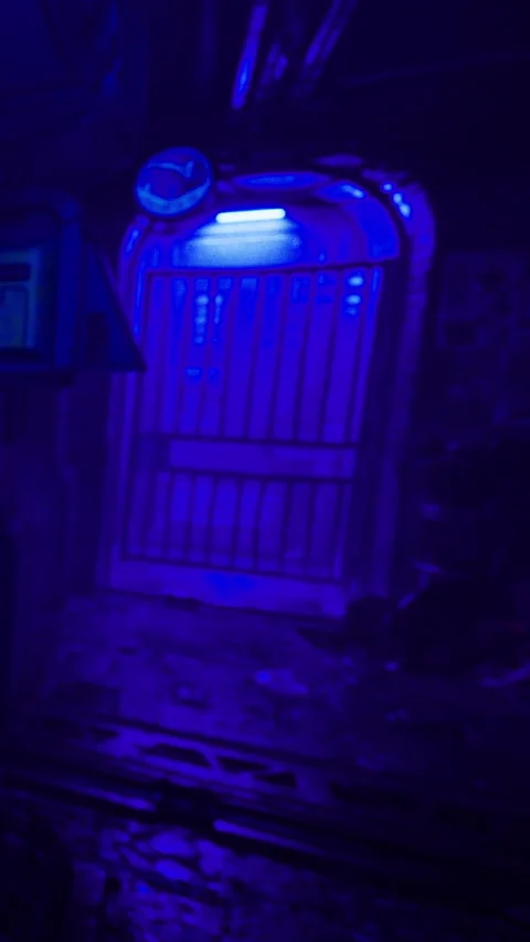 Bright blue light illuminates a gate in a dimly lit space at night Stock Footage 331770263