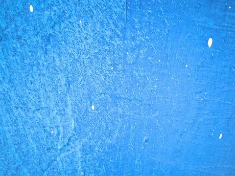 Bright blue painted wall texture with white paint splatters close up Stock Photos